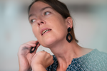 Woman wearing black earrings looking upwards with a neutral expression.