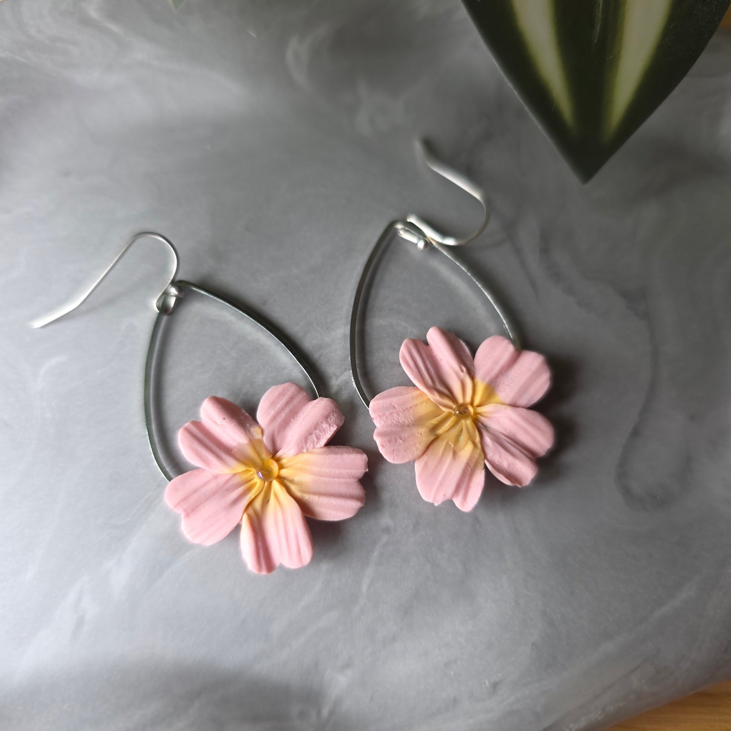 Handgemaakte bloemen in pastelroze aan zilveren druppel